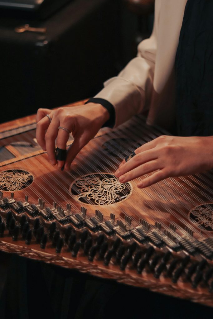 pexels-photo-10879958-10879958 An artistic close-up of hands tuning a traditional kanun string instrument, highlighting intricate details.