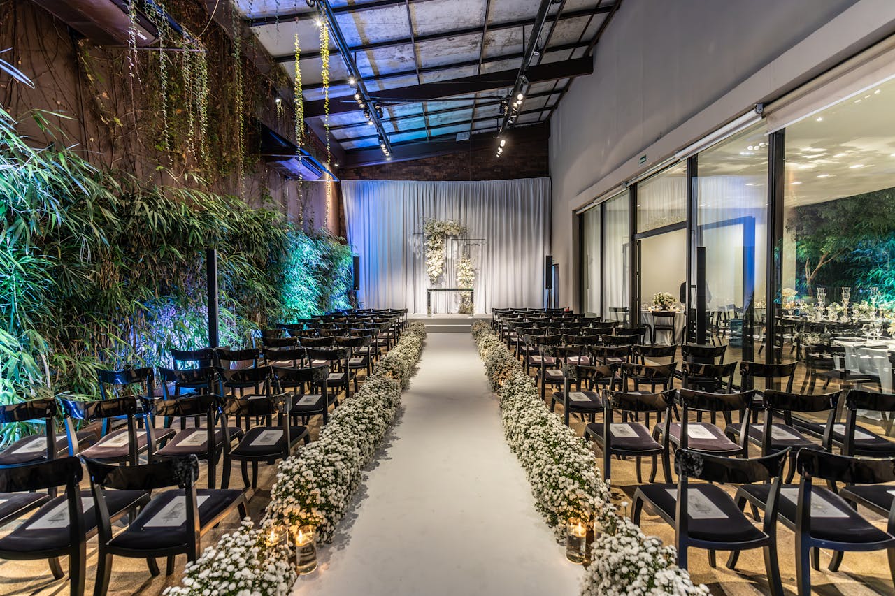 Beautifully decorated wedding venue with aisle, chairs and floral arrangements indoors.